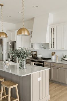 a large kitchen with an island and two stools in front of the counter top