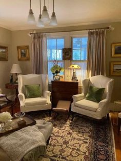 a living room with two chairs and a rug in front of a window that has curtains on the windowsill