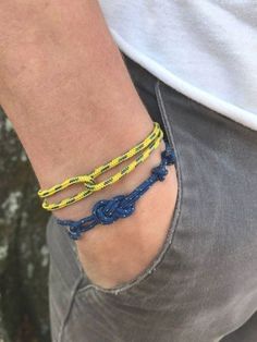 a person wearing two different bracelets on their wrist and one has a yellow rope attached to it