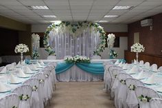 a banquet hall with tables and chairs covered in white linens, blue sashes and flowers