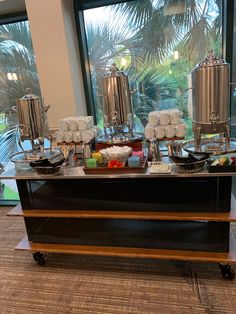 an assortment of desserts and pastries on a buffet table in front of a large window