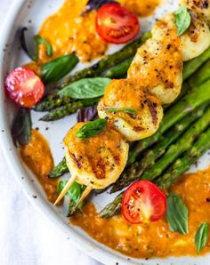 grilled shrimp and asparagus with tomato sauce on a white plate, ready to be eaten