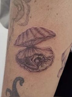 a close up of a person's leg with tattoos on it and a shell