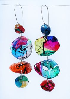 four colorful earrings hanging from hooks on a white background with the word love painted on them