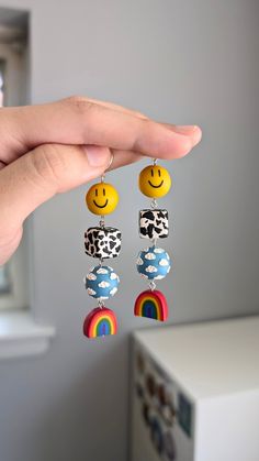 a pair of earrings with smiley face charms hanging from it's ear hooks in front of a white wall