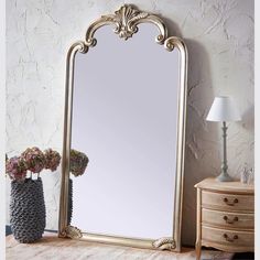 a large mirror sitting on top of a wooden table next to a vase with flowers