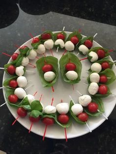 a white plate topped with green leafy vegetables and skewered meatballs on toothpicks