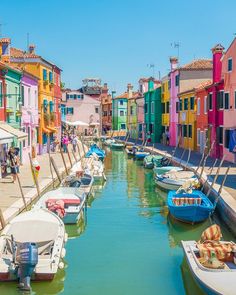 boats are parked along the side of a canal in front of colorful buildings and shops