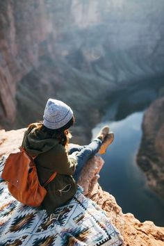 a woman sitting on top of a mountain next to a lake with a quote above her