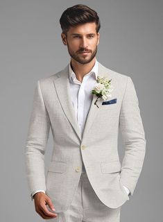 a man in a gray suit with a flower on his lapel and white shirt