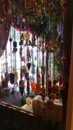 a window display with lots of necklaces hanging from it's sides and on the windowsill