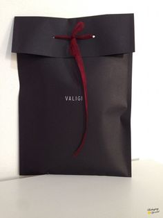 a black bag with a red ribbon tied around it and the word valigi written on it