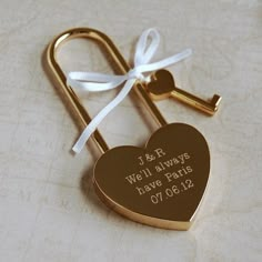 a gold heart shaped key with a white ribbon tied around it and the words i & r well always have paris on it