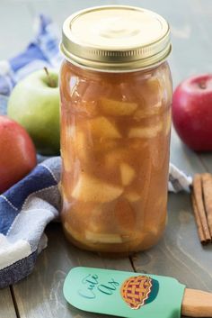 an apple cider in a mason jar next to apples and cinnamon sticks