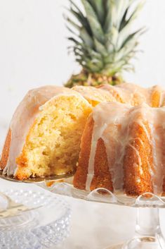 a pineapple bunt cake with white icing on a glass plate next to a pineapple