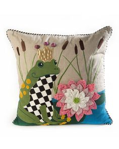 a decorative pillow with a frog and flower on the front, sitting against a white background