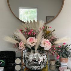 a disco ball vase filled with flowers on a table next to a mirror and other items