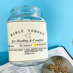 a glass jar filled with bible verses next to an open book