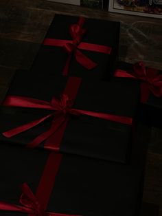 two black wrapped presents with red ribbon on them