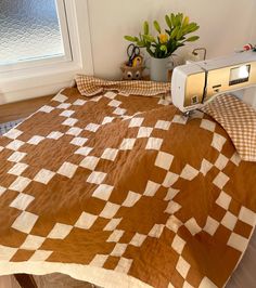 a bed with a brown and white checkered bedspread next to a window