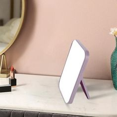 a small mirror sitting on top of a table next to a vase