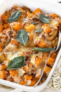 a casserole dish with cheese and sage leaves on top, ready to be eaten