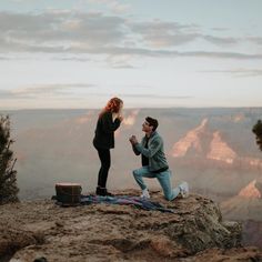 a man kneeling down next to a woman on top of a mountain