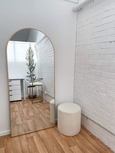 a white room with a large mirror and stool