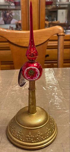 a red glass candle holder sitting on top of a table next to a wooden chair