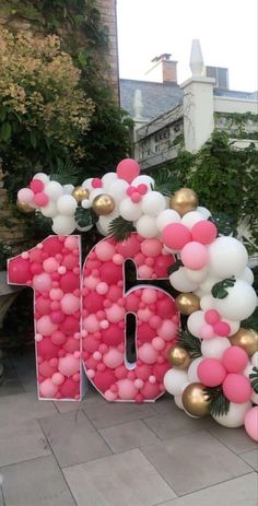 the number sixteen balloon arch is decorated with pink, white and gold balloons