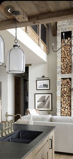 a living room filled with furniture next to a firewood stack and a stone fireplace