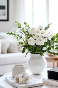 a white vase filled with flowers sitting on top of a table next to a book