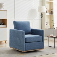 a blue chair sitting in a living room next to a lamp