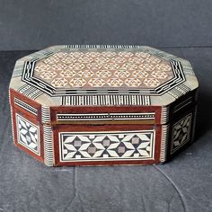 an ornate wooden box sitting on top of a gray surface with geometric designs inlays