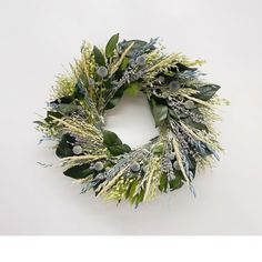 a wreath with green leaves and white flowers on the front is displayed against a white background