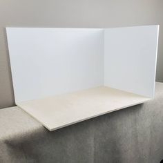 an open white box sitting on top of a table next to a gray couch and wall