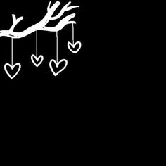 a tree branch with hearts hanging from it's branches on a black background in the dark