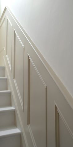 a cat is sitting on the stairs next to some white walls and carpeted floor