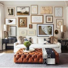 a living room filled with lots of pictures on the wall above a white couch and coffee table