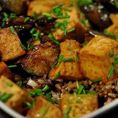 a white bowl filled with tofu and rice covered in green garnishes