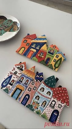 two small ceramic houses sitting on top of a table next to a plate and bowl