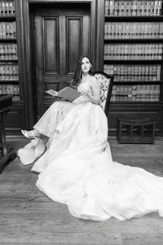 black and white photograph of a woman in a wedding dress sitting on a chair reading a book