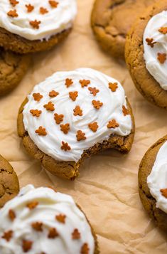 cookies with white frosting and orange sprinkles are arranged on parchment paper