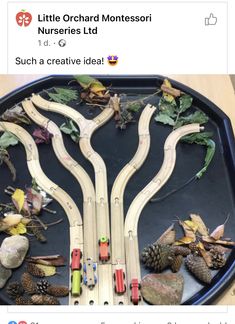 a toy train set sitting on top of a table next to leaves and pine cones