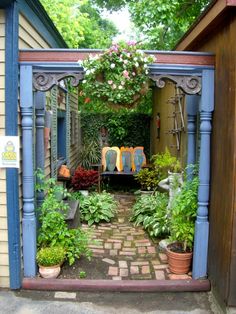 an outdoor garden with potted plants and flowers in the doorway to a building that has a brick walkway leading into it