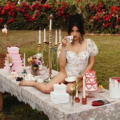 a woman sitting at a table with cake, candles and other items on the table