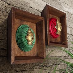 two wooden wall plaques with gold and red designs on them hanging from a brick wall