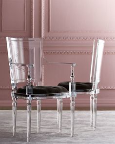 two clear chairs sitting next to each other in front of a pink wall and floor