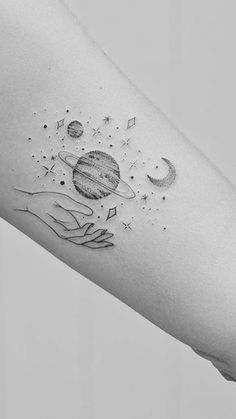 an arm tattoo with two hands holding planets and stars