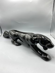 a black glass leopard figurine sitting next to a pair of glasses on a white surface